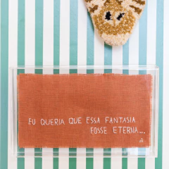 Quadro decorativo com caixa de acrílico e linho terroso, exibindo a frase "Eu queria que essa fantasia fosse eterna..." em letras brancas.