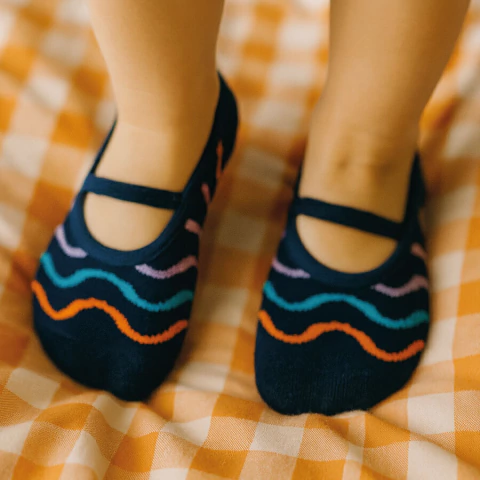 Sapatilha infantil Cantarola modelo Rabiscos, azul marinho com detalhes coloridos, nos pés de uma criança.