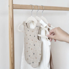 Set de cabides de veludo off-white da marca 3 Sprouts organizando roupas infantis em um cabideiro de madeira.