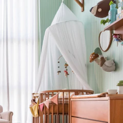 Tenda infantil tule branco com quatro camadas Sam&Peas decorando quarto de criança, ao lado de cama com dossel e almofadas coloridas.