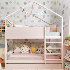 Cama beliche infantil decorada com almofadão de encosto Vichy e outras almofadas coloridas em quarto de bebê com papel de parede lúdico.