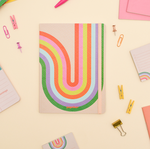 Cuaderno tapa blanda tamaño 14x19 cm con diseño de líneas curvas multicolores sobre fondo rosita