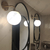 Aplique de pared curvo con esfera blanca iluminada en un baño moderno.