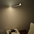 Lámpara LED lineal colgante encendida sobre una mesa de oficina.