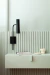 Aplique de pared Cavia de brazo corto en un ambiente interior con una pared de color verde claro y una mesa con objetos decorativos.