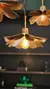 Lámpara colgante Amapola Rugosa de una luz con diseño de pétalos dorados y bombilla iluminada.