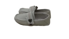 Um par de sapatos Klin em tom cinza claro, com detalhes em costura e fechamento em velcro, sobre uma superfície felpuda.