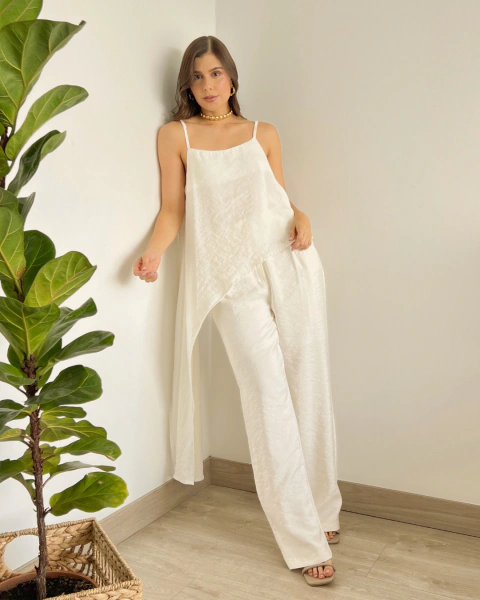 Conjunto blanco T.203 de PRIMIA, vista frontal de cuerpo completo mostrando el movimiento del top asimétrico y el pantalón largo.