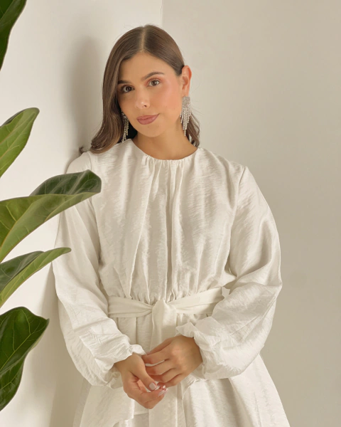 Detalle frontal del Vestido T.153 Blanco de PRIMIA, con cuello redondo fruncido, mangas largas amplias y cinturón en la cintura.