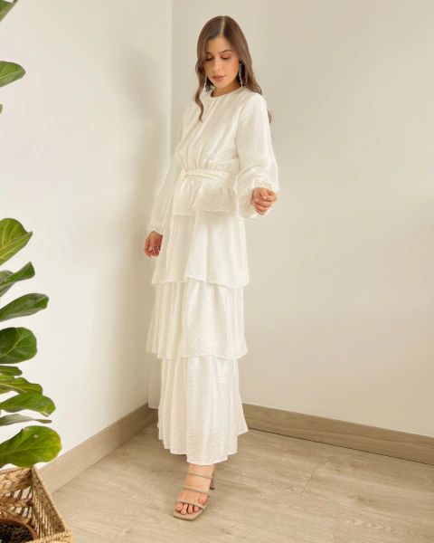 Vestido Largo T.153 Blanco de PRIMIA, vista lateral de cuerpo completo mostrando la cintura definida y la falda de capas con volantes.