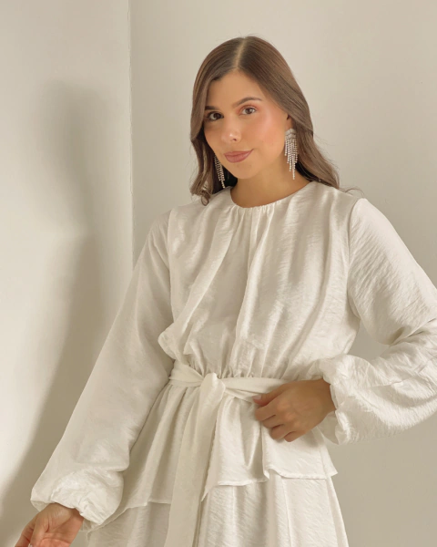 Detalle superior del Vestido T.153 Blanco de PRIMIA, con cuello redondo, mangas largas de puños recogidos y cinturón anudado.