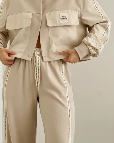 Detalle frontal del Set T.119 Crema de PRIMIA, mostrando los bolsillos con tapa, botones a tono y cintas VINTAGE NATURAL en el pantalón.