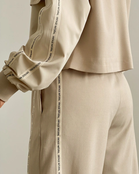 Primer plano del Set T.119 Crema de PRIMIA, con detalle de las cintas decorativas en la manga y el costado del pantalón.