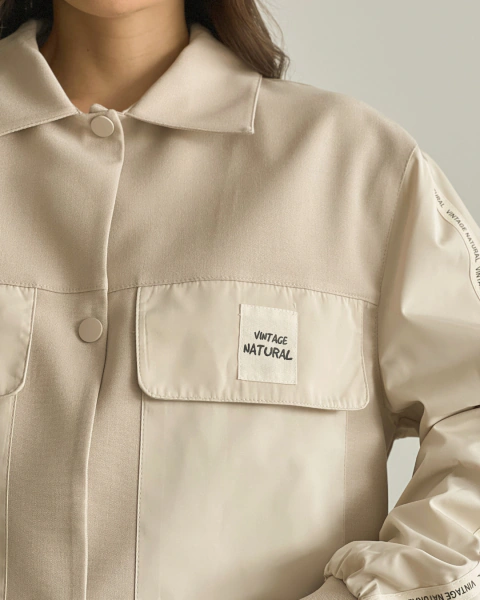 Detalle frontal de la chaqueta del Set T.119 Crema de PRIMIA, mostrando el cuello camisero, los botones y el bolsillo con etiqueta VINTAGE NATURAL.