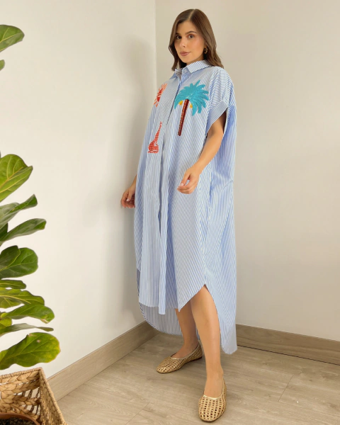 Vestido largo P.080 de PRIMIA, vista frontal en ángulo con cuello camisero, manga corta amplia, aplicaciones tropicales y abertura lateral.