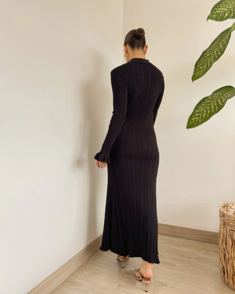 Vista posterior de cuerpo completo del vestido T.202 negro de PRIMIA con manga larga y terminación ondulada.