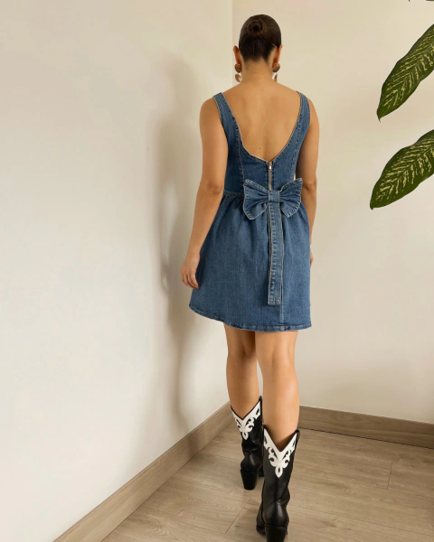 Vestido denim T.174 de PRIMIA, vista posterior con escote profundo, cierre y lazo grande en la espalda.