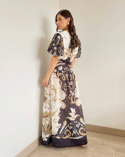 Vestido T.146 de PRIMIA, vista posterior en ángulo de cuerpo completo con estampado floral ornamental, cintura definida y falda larga de corte amplio.