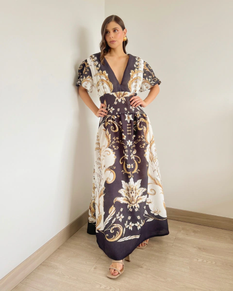 Vestido T.146 de PRIMIA, vista frontal de cuerpo completo con manos en la cintura, escote en V y estampado floral ornamental distribuido en toda la prenda.