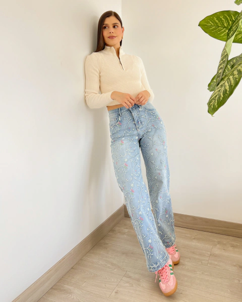 Jean NOHELA Azul de PRIMIA, vista frontal de cuerpo completo con acabado denim azul claro, bordados florales distribuidos en ambas piernas y silueta amplia.