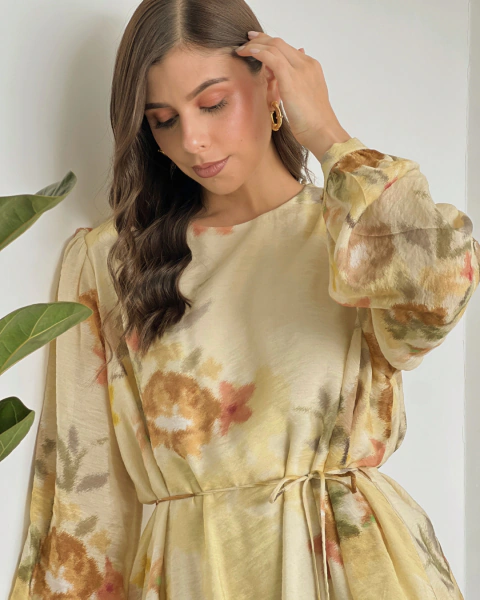 Primer plano del vestido T.168 de PRIMIA, con estampado floral en tonos café, rosado y verde, manga larga y detalle de ajuste en la cintura.
