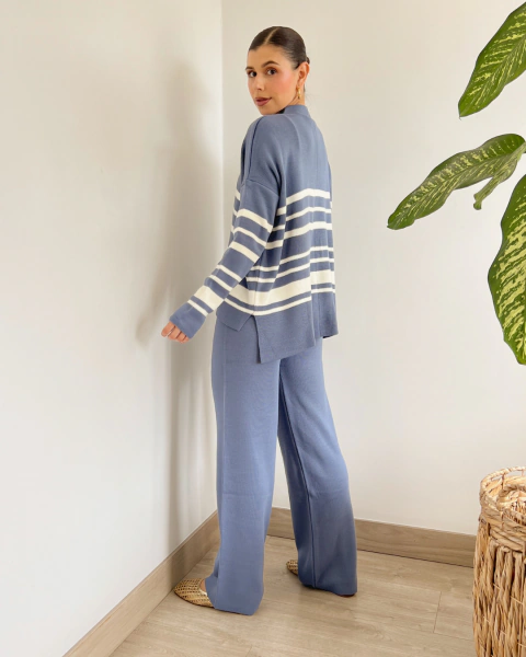 Conjunto azul de PRIMIA, vista lateral de cuerpo completo que muestra el buzo holgado de manga larga con rayas blancas y el pantalón amplio.