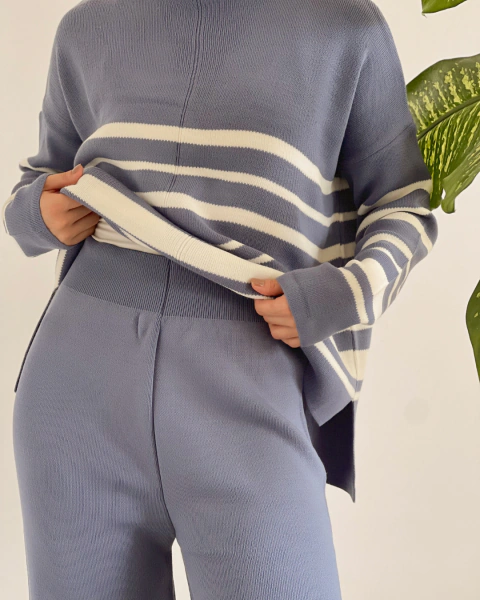Conjunto azul de PRIMIA, primer plano de la cintura del pantalón con pretina elástica y textura de punto, junto al detalle de las rayas blancas del buzo.