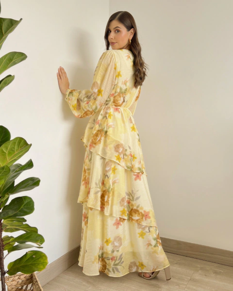 Vestido floral largo T.168 de PRIMIA, vista posterior lateral con estampado en tonos tierra, cintura definida y falda de capas asimétricas.