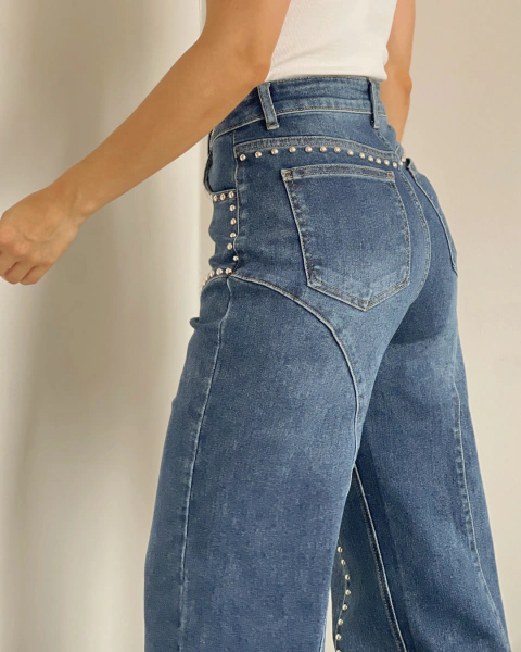 Detalle lateral y posterior del Jean P.096 de PRIMIA, con taches plateados alrededor de la cadera y costuras curvas sobre el denim azul.