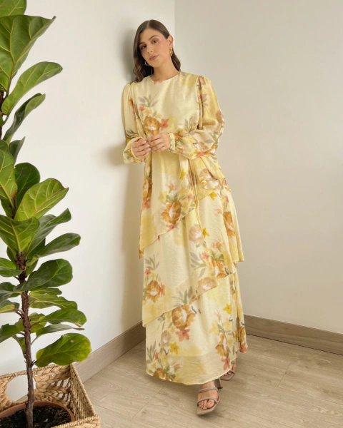 Vestido floral amarillo T.168 de PRIMIA, vista frontal de cuerpo completo con falda larga asimétrica, mangas abullonadas y estampado floral multicolor.