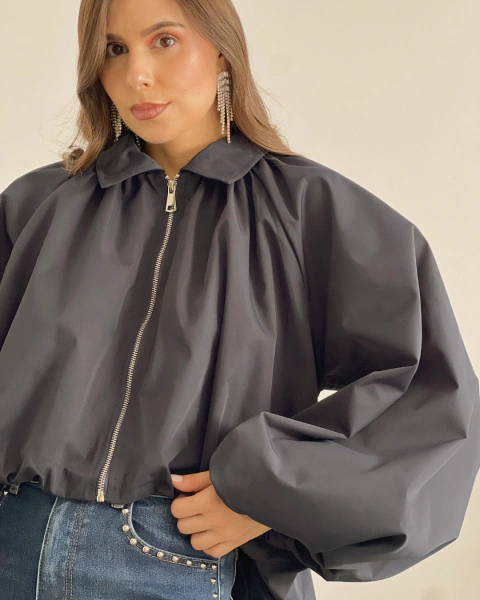 Primer plano de la Chaqueta P.079 de PRIMIA en azul oscuro, con detalle del cuello camisero, los pliegues superiores, la cremallera metálica y las mangas abullonadas.