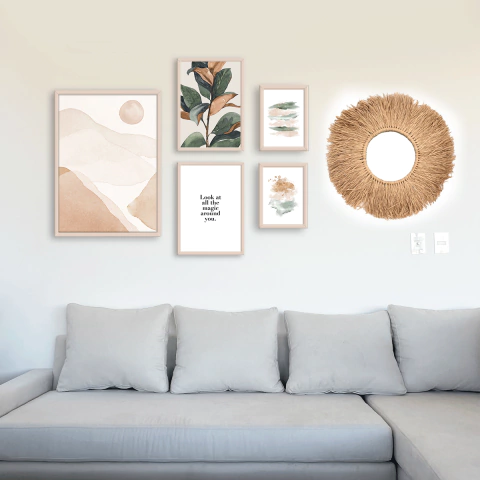 Set de cinco cuadros decorativos con ilustraciones botánicas y frases, junto a un espejo redondo con marco de fibras naturales, sobre pared blanca en living con sofá gris.