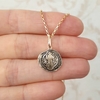 Colar folheado a ouro com medalha de São Bento em destaque, segurado por uma mão.