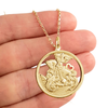 Colar folheado a ouro com medalha de São Jorge, segurado por uma mão.