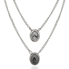 Escapulário de aço inox com dois medalhões ovais, um com imagem religiosa e outro com a representação de uma igreja, em preto e branco.