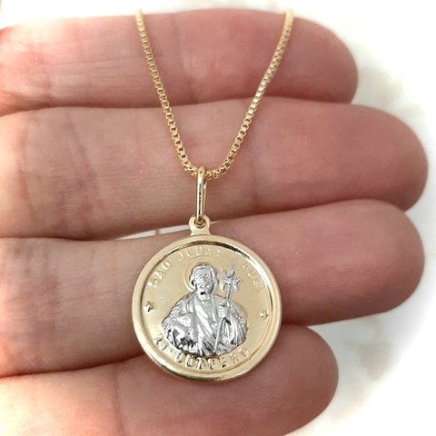 Colar folheado em ouro com medalha de São Judas, segurado na mão.