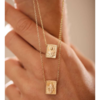 Escapulário Nossa Senhora do Carmo em estilo retangular, com detalhes em dourado, pendurado em uma mão.