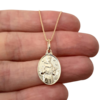 Colar folheado a ouro com medalha de São Francisco, segurado na mão.