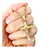 Colar cruz de São Bento em aço, segurado na mão, com corrente dourada de 60 cm.
