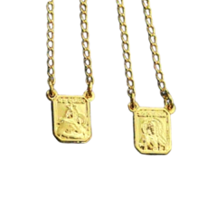Escapulário N S Carmo Pequeno Folheado em metal dourado, com duas medalhas penduradas, uma representando a imagem de Nossa Senhora do Carmo e outra de Santa Teresa de Ávila.