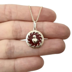 Colar folheado com pingente em formato de coração vermelho, segurado por uma mão.