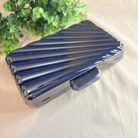 Bolsa clutch de festa em metal prateado com frisos nas laterais, fecho de encaixe e alça de ombro metálica. Elegância e sofisticação para eventos especiais.