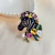 Broche de zebra com flores coloridas e aplicação de pedras brilhantes. Um acessório criativo, elegante e cheio de personalidade para dar vida aos seus looks.