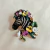 Broche de zebra com flores coloridas e aplicação de pedras brilhantes. Um acessório criativo, elegante e cheio de personalidade para dar vida aos seus looks.