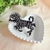 Broche elegante em formato de zebra com aplicação de pedras brilhantes e acabamento em preto e dourado. Um toque sofisticado e divertido para qualquer look.

