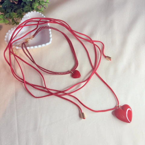 Colar duplo com cordão tipo courino vermelho, rebites dourados e pingente de coração em resina. Estilo moderno e ousado para looks autênticos.