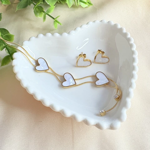 Conjunto colar gravatinha e brinco de coração com efeito madrepérola em aço inox dourado. Feminino, resistente e hipoalergênico.