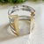 Pulseira bicolor em metal com design moderno, exibindo faixas prateadas e douradas.