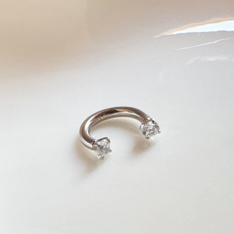 Piercing ferradura com pedras de zircônia e rosca interna em aço cirúrgico. Brilho delicado, hipoalergênico e ideal para vários tipos de furo. Conforto e segurança no seu dia a dia.