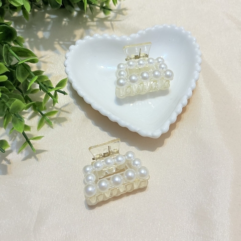 Piranha de cabelo pequena em formato retangular, com mini pérolas brancas e base em acrílico transparente. Ideal para prender pequenas mechas com charme e delicadeza.